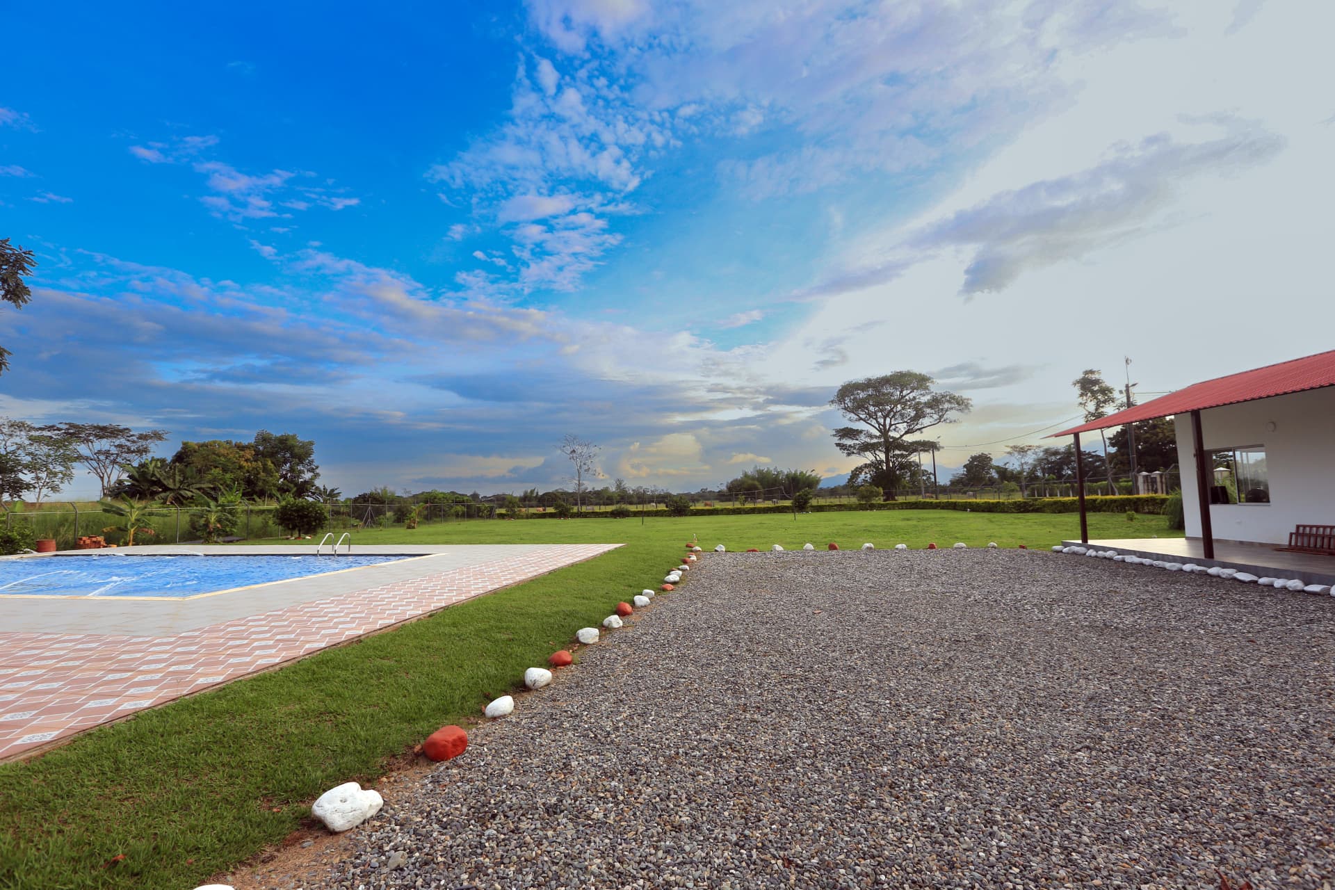 Piscina y amplia zona verde de Finca Mana bajo el cielo azul